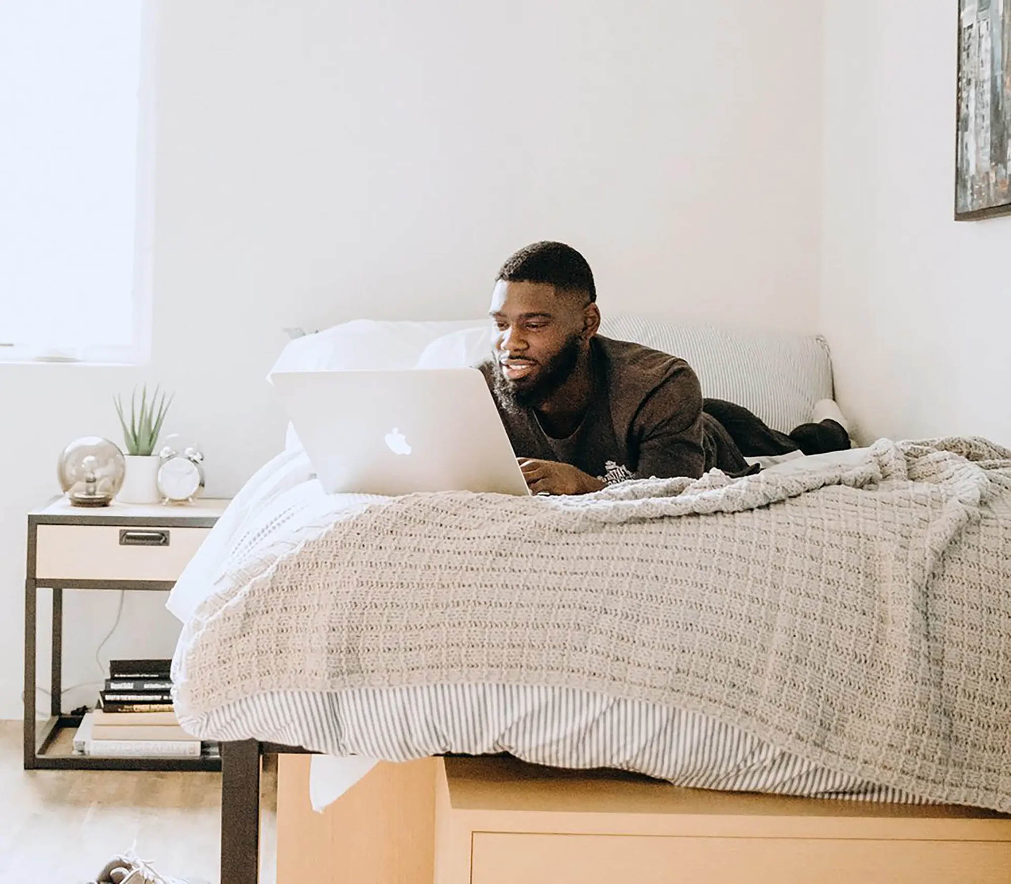 Man lying on bed with his laptop open