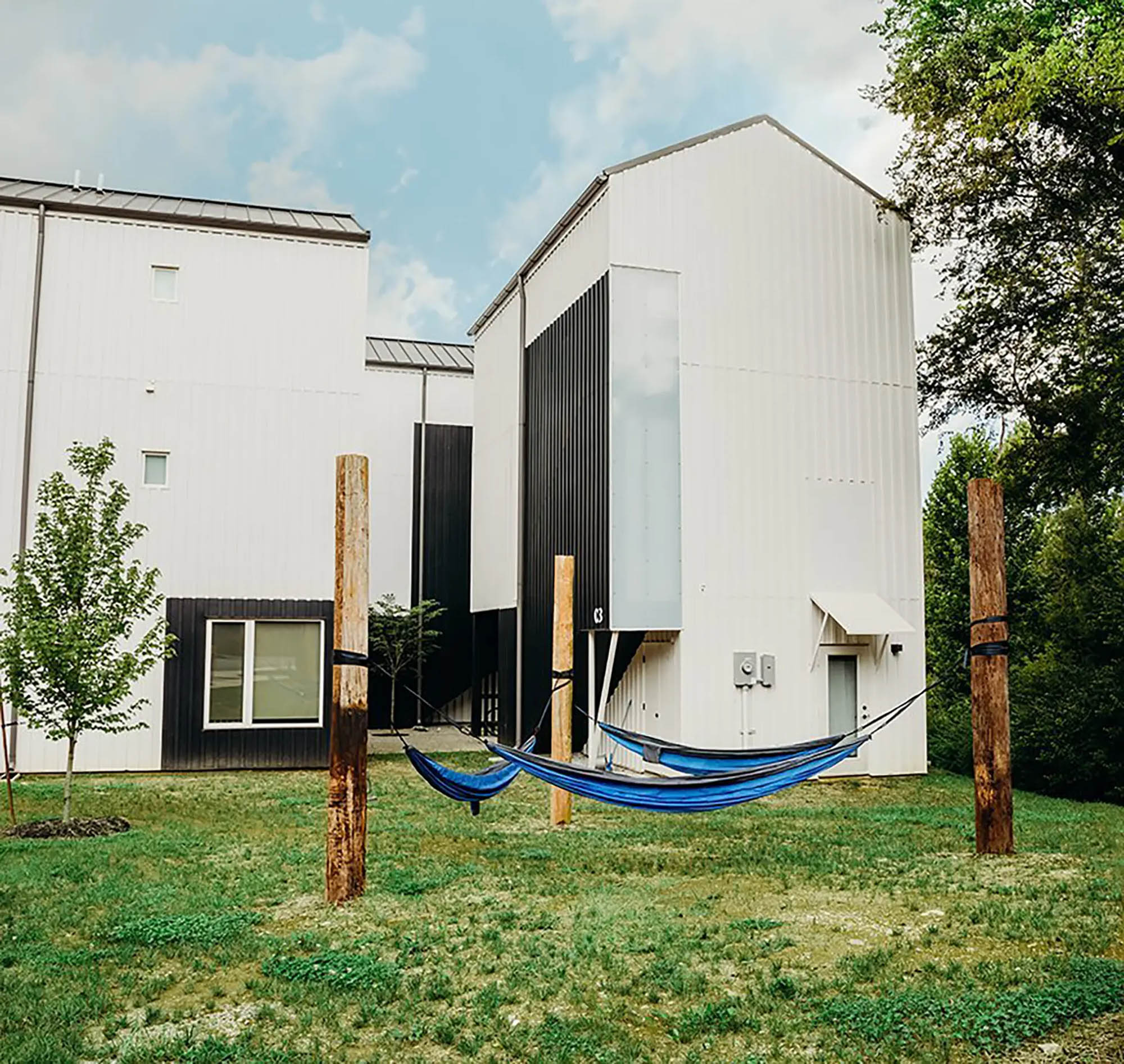 Series of three blue hammocks hung outside of modern apartment complex